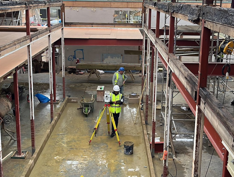 A construction site with professionals using advanced technology to set out construction elements accurately. The setting should be busy and depict teamwork in action.